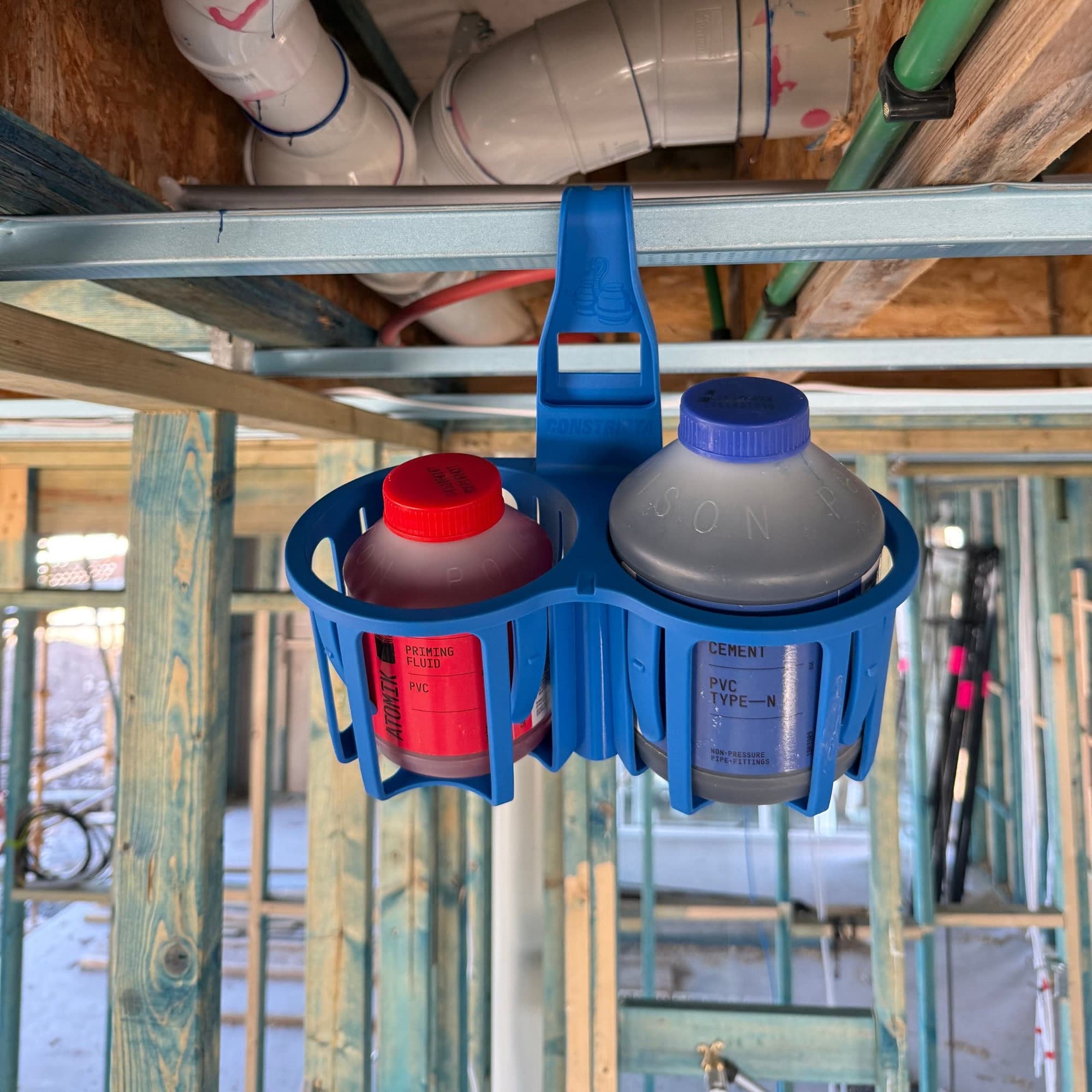 Blue bottle holder with two bottles hanging from it in a construction setting.