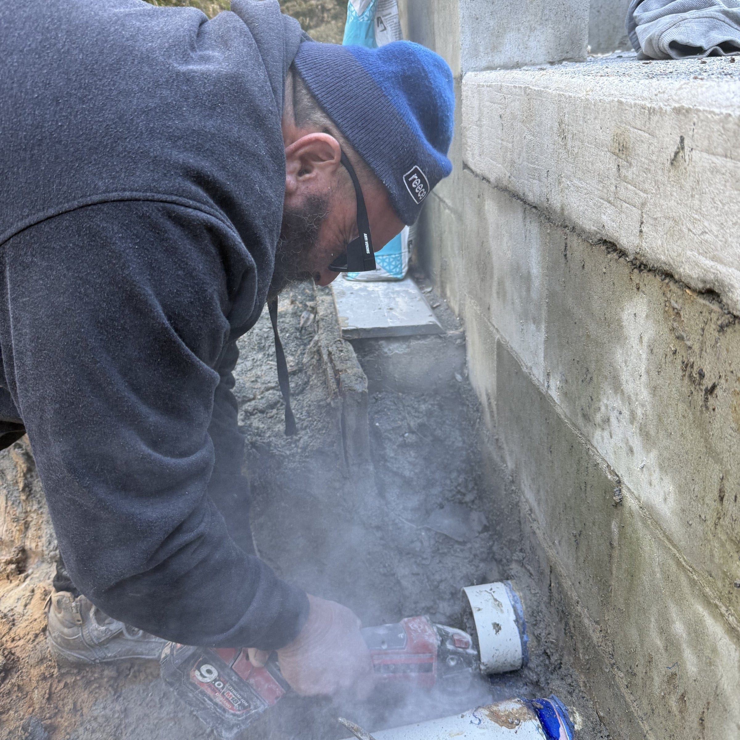 Plumber wearing anti venoms - polarized safety glasses while he grinds concrete the glasses protect hes eyes from the dust